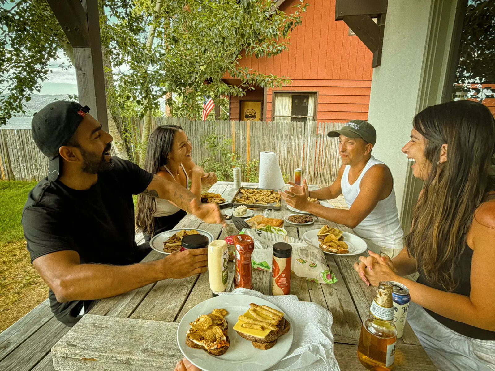Kyle and friends laughing over lunch at a long outdoor table