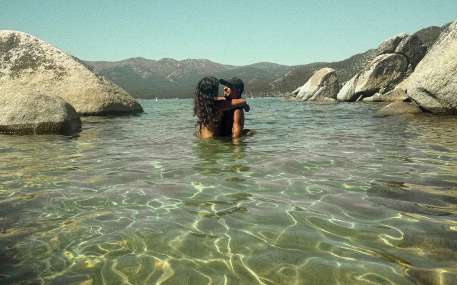 Kyle Lasota in the shallows at Lake Tahoe, holding someone close